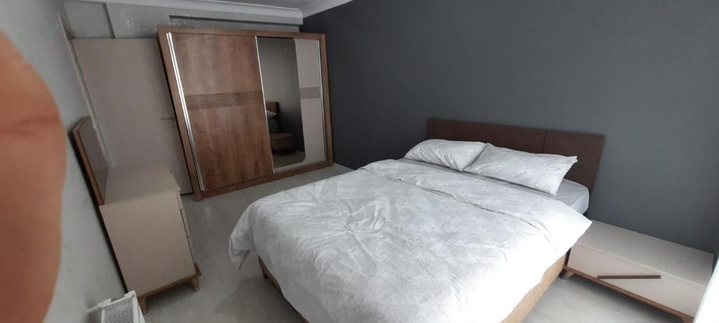 um pequeno quarto com uma cama branca e um espelho em شقة مفروشة للايجار باسطنبول em Basaksehir