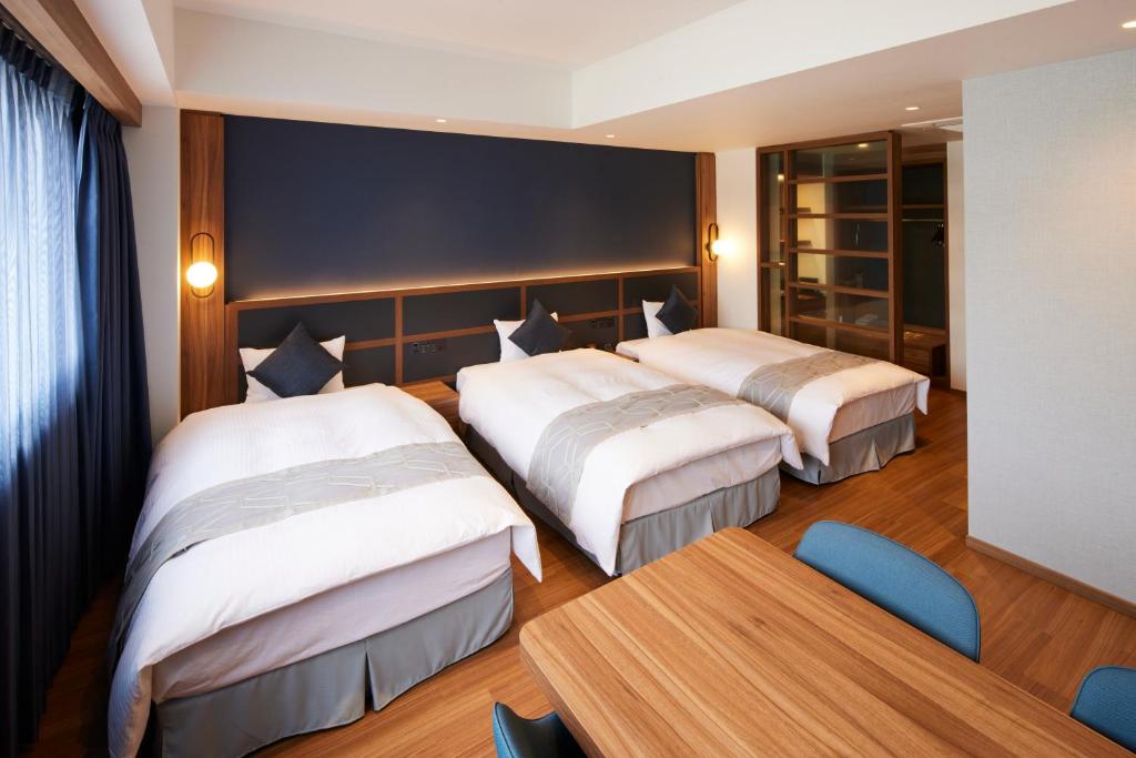 a hotel room with three beds and a table at HOTEL SAILS in Osaka