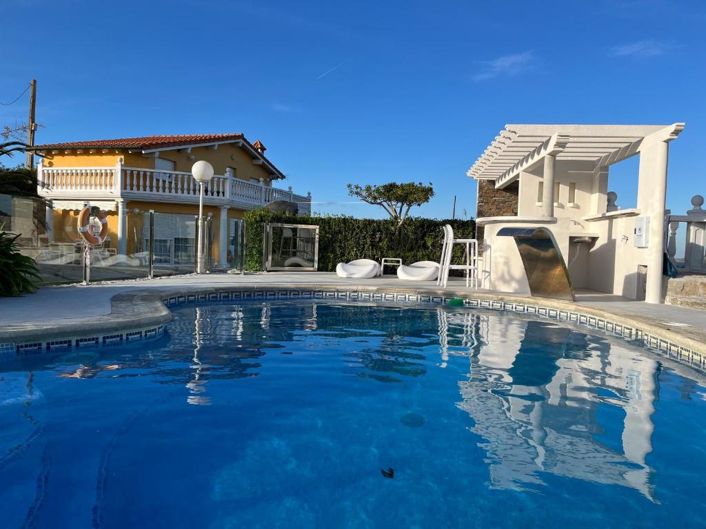 a swimming pool in front of a house at Chalet Robayera a línea de playa in Miengo