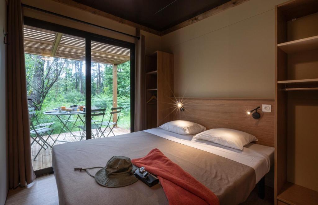 a bedroom with a bed and a balcony with a table at CityKamp Lyon in Dardilly