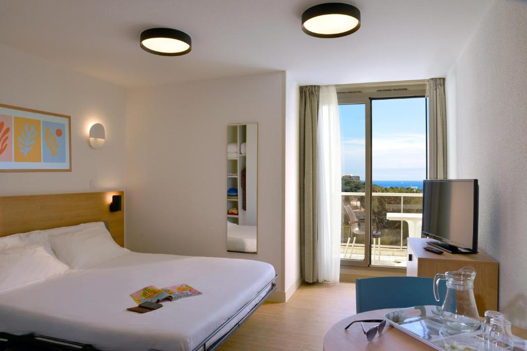 a hotel room with a bed and a table and a television at Residence Residéal Antibes in Antibes