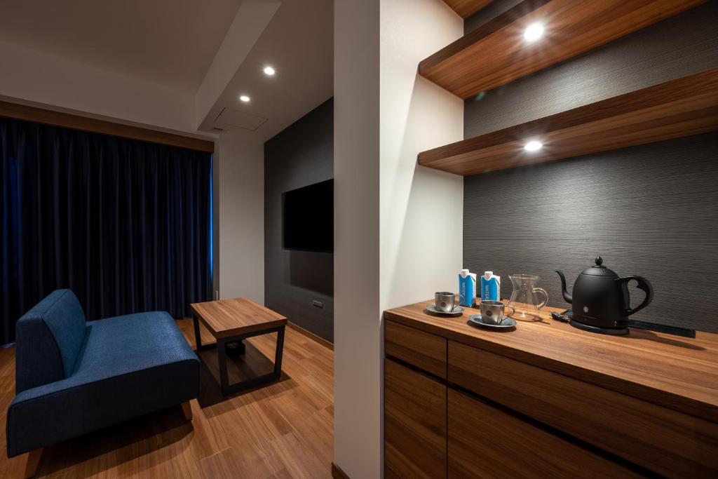 a room with a blue chair and a television at HOTEL SAILS in Osaka