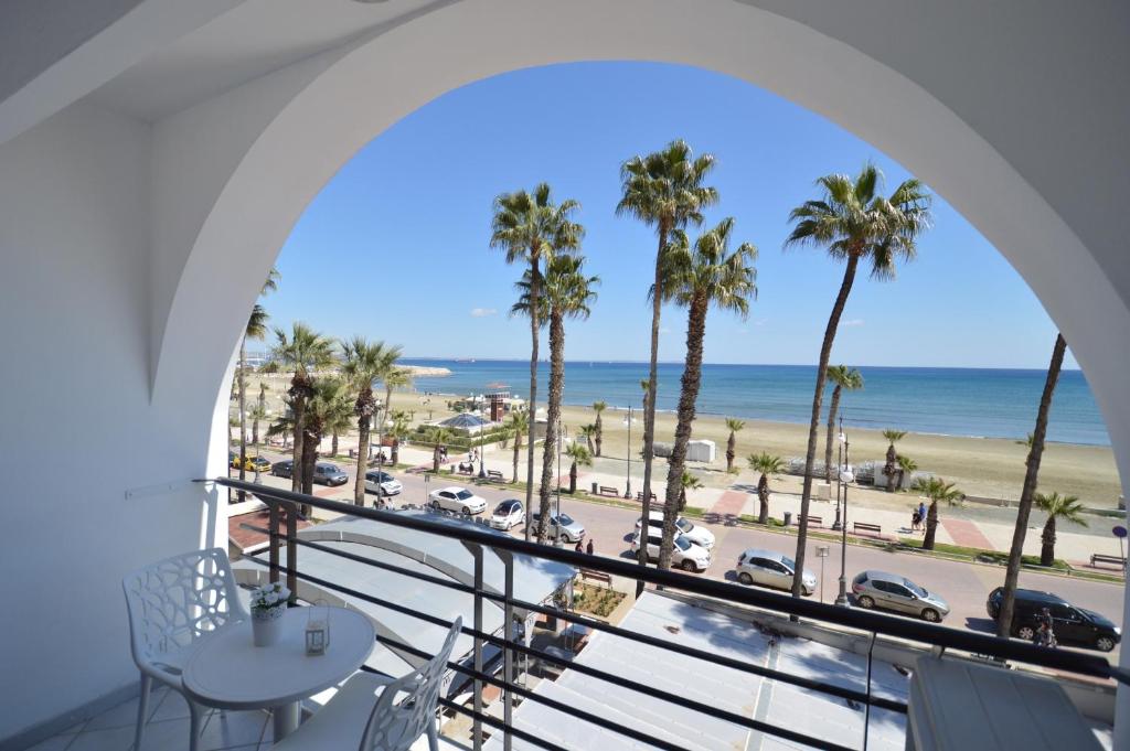 einen Balkon mit Blick auf den Strand und die Palmen in der Unterkunft Krasas Beach Apartment Rentals in Larnaka
