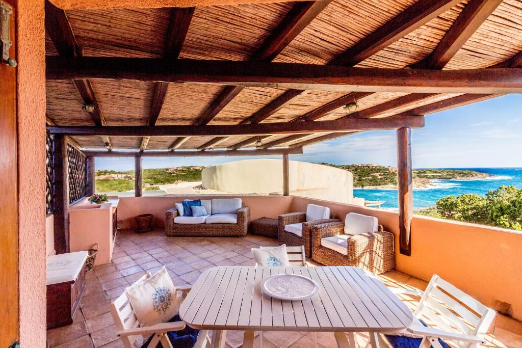 a patio with a table and chairs and the ocean at Cala Flores Sea View Apt 400m from the beach! in Porto Cervo