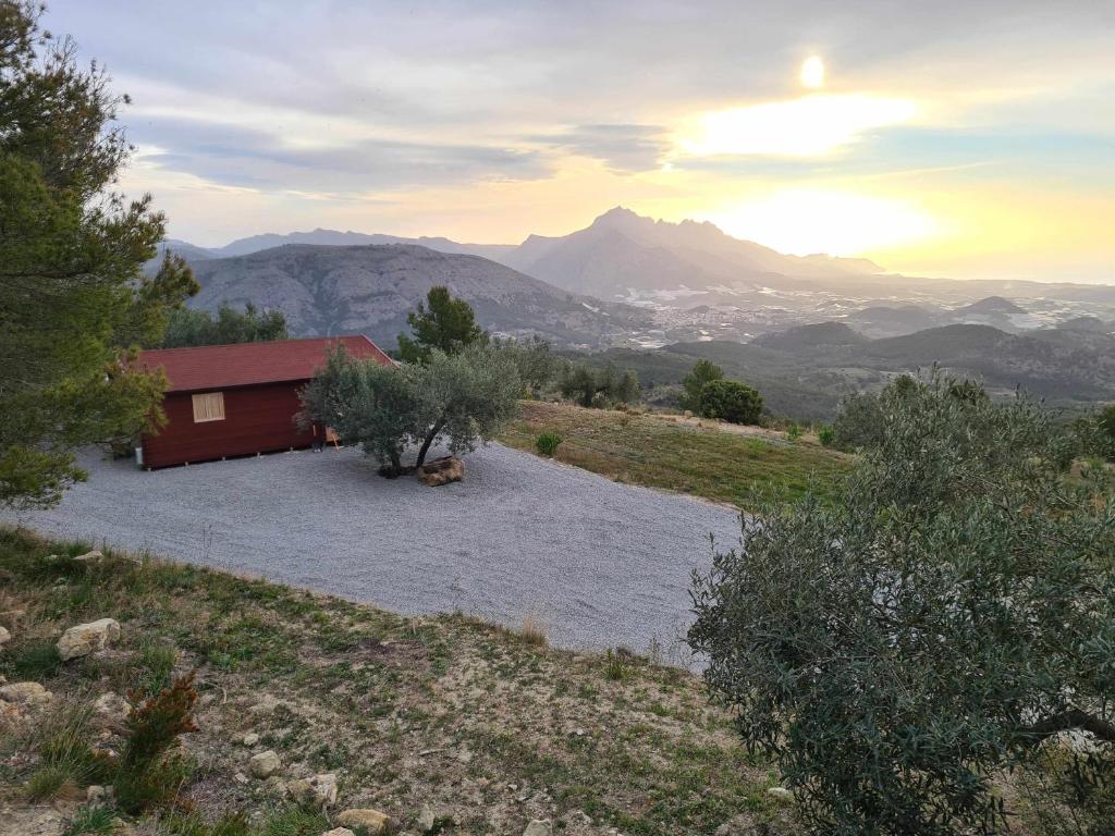 a red house on a hill with mountains in the background at Cabañas by Torre de Arriba in Benimantell