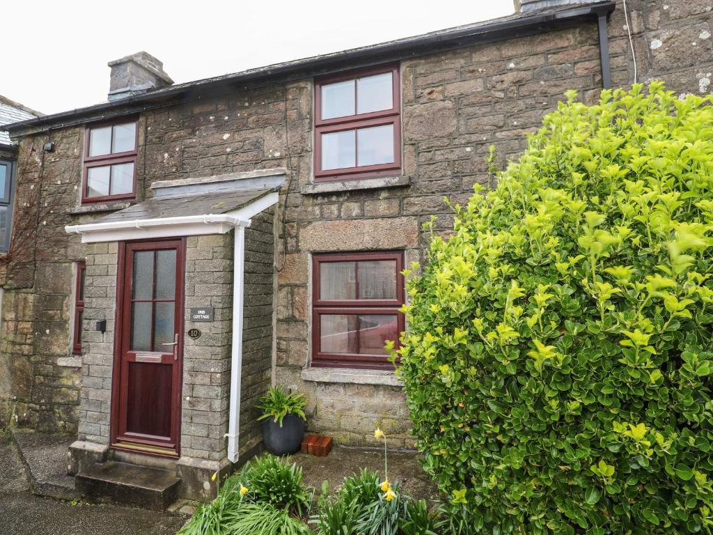 an old stone house with a red door at Iris Cottage in Penzance