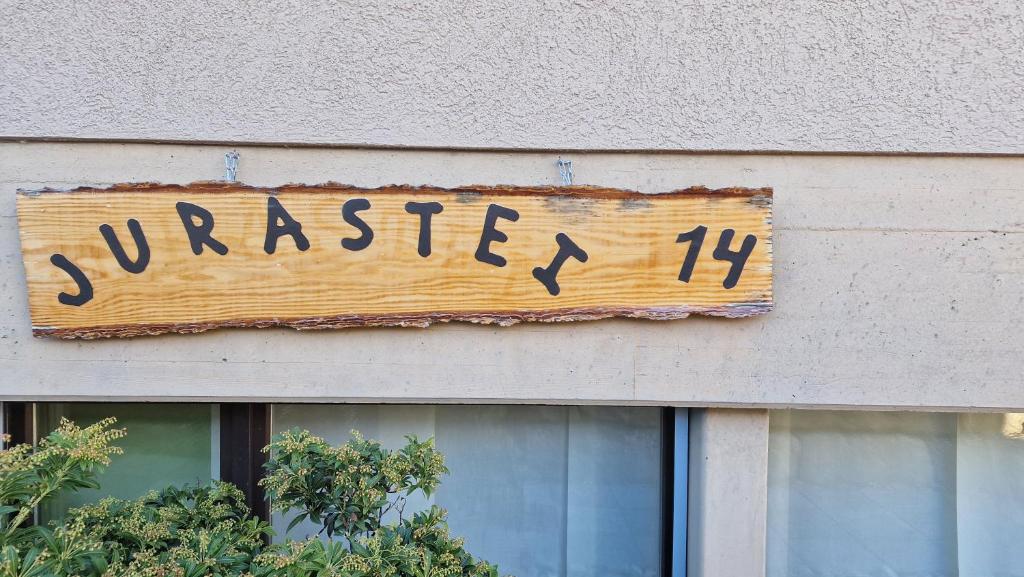 un cartel de madera en el lateral de un edificio en Jurastei14, en Wiedlisbach