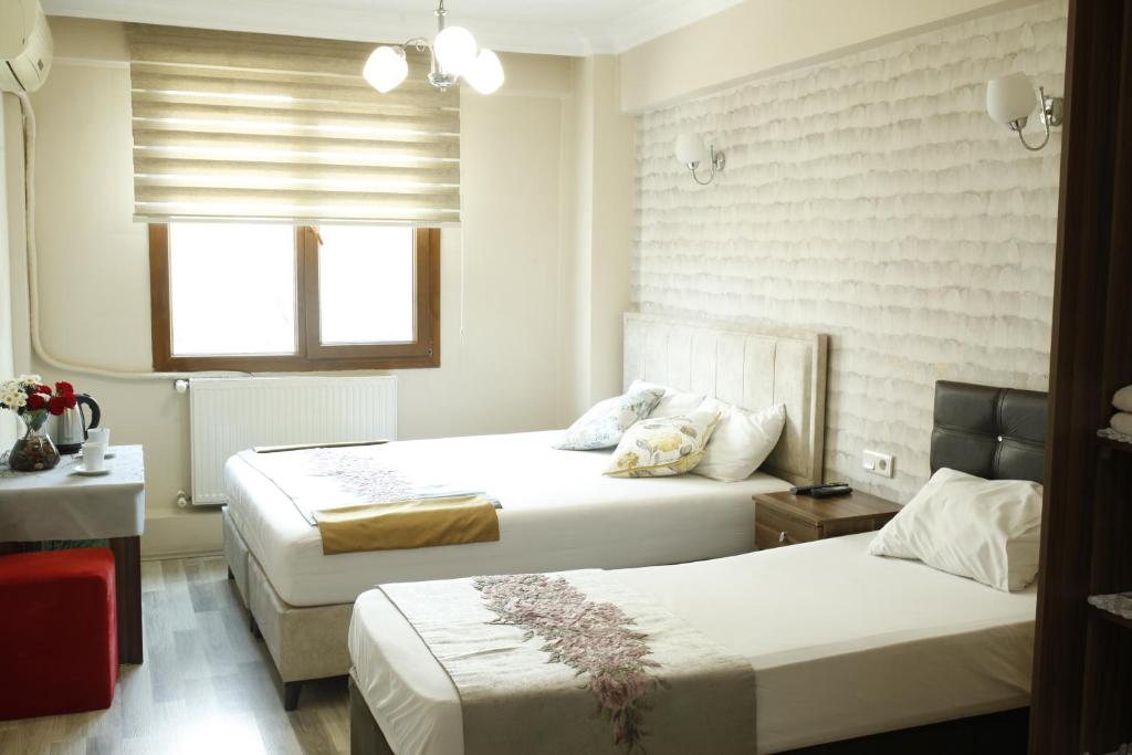 イスタンブールにあるビルリック アパート ホテルのベッド2台と窓が備わるホテルルームです。