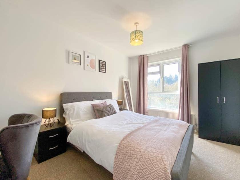 a bedroom with a bed and a chair and a window at Scarlet House in Batheaston