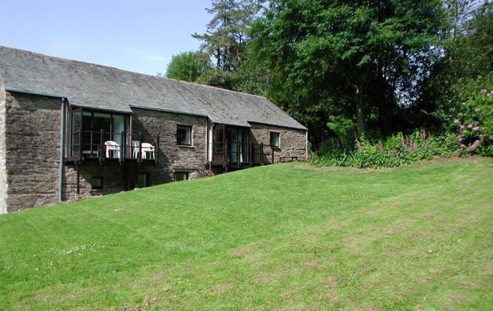 uma casa de pedra numa colina com um jardim verde em Grange Cottage Lakeside Windermere em Newby Bridge