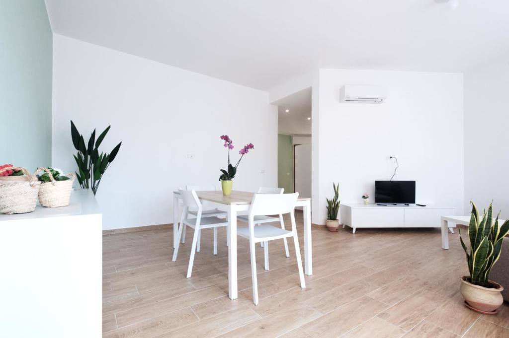 a white living room with a table and chairs at [Relax-Comfort-Home] City Center in Porto Torres
