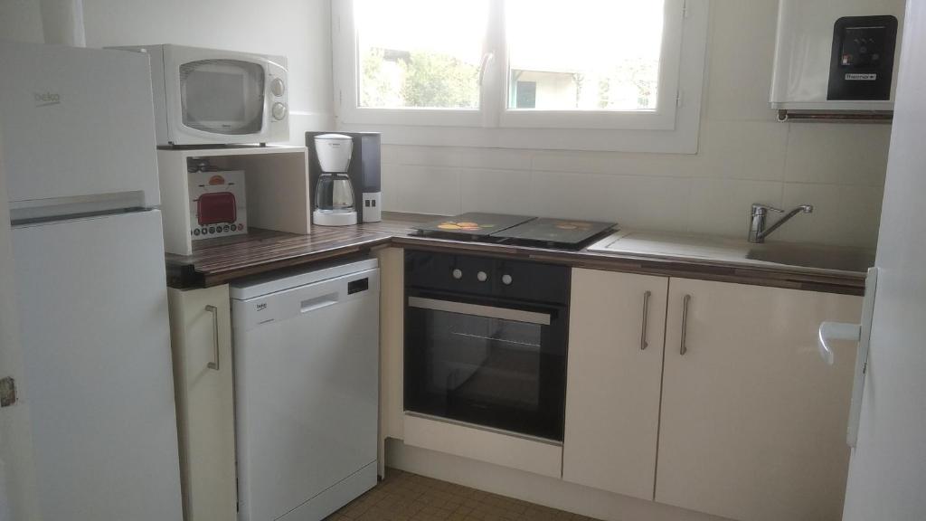 kuchnia z białymi szafkami i czarnym piekarnikiem w obiekcie Idéalement situé, tout à pied, 60m2 w mieście Saint-Georges-de-Didonne