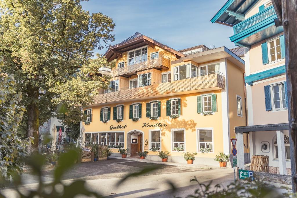 een groot geel gebouw met een balkon bij Hotel Kendler in Sankt Gilgen