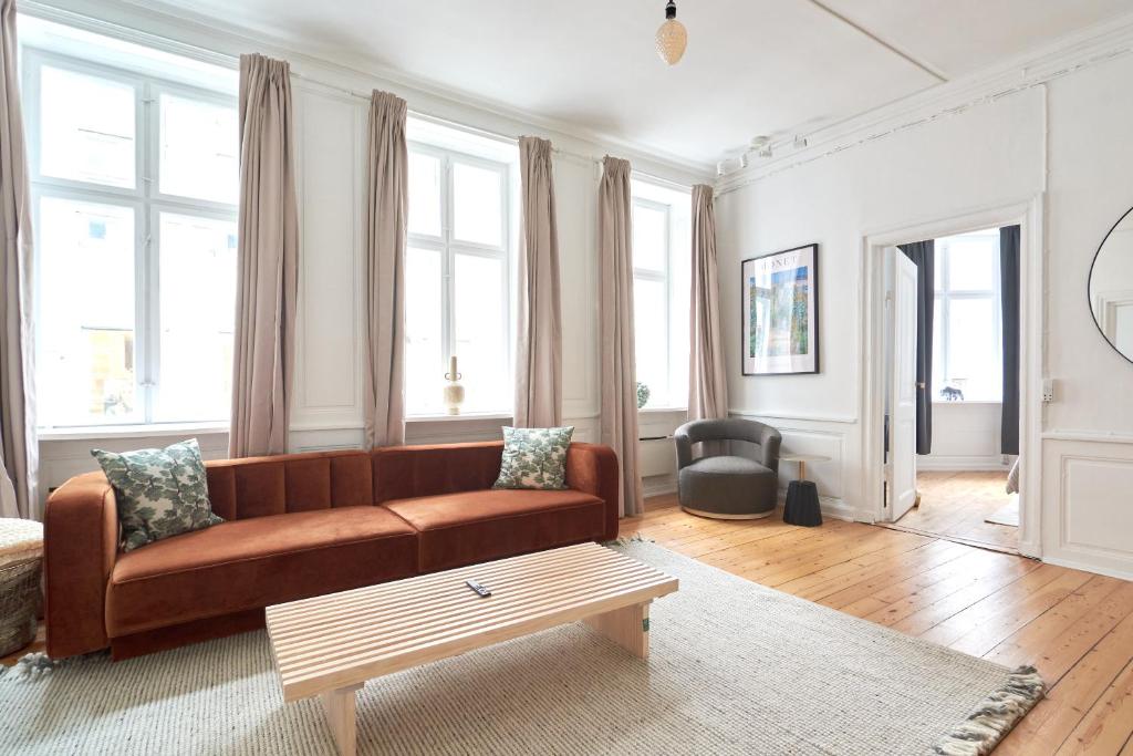 a living room with a brown couch and some windows at Bright Apartment in the Old Town of Copenhagen in Copenhagen