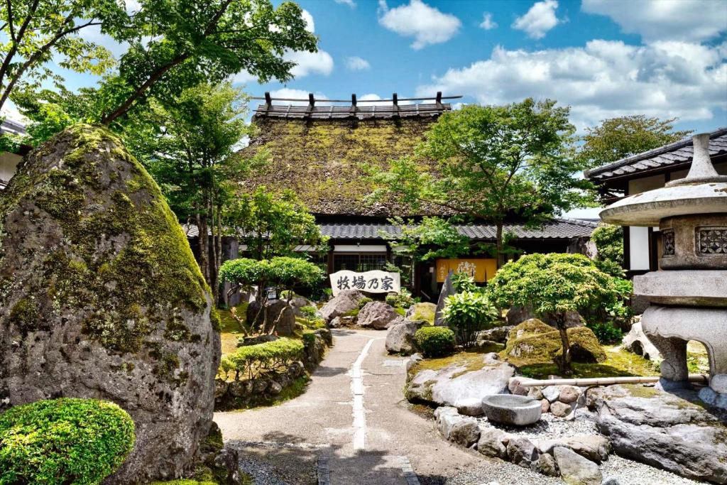 a garden in front of a building with rocks and trees at Ryosou Makibanoie 18 years or older in Yufuin