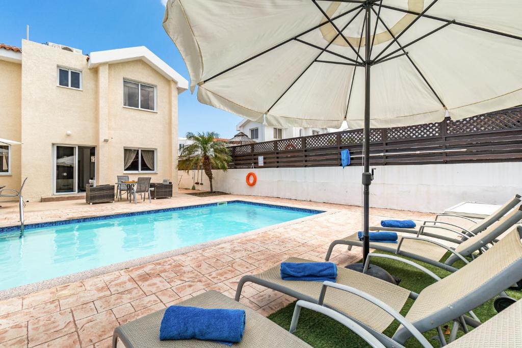 - une piscine avec des chaises et un parasol à côté d'une maison dans l'établissement Villa Sunnyside Mandali by Ezoria Villas, à Protaras