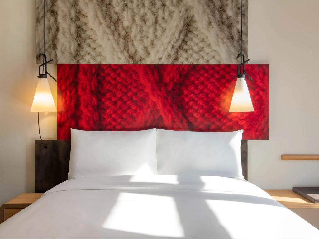 uma cama com duas almofadas brancas e uma cabeceira vermelha em ibis Doha em Doha