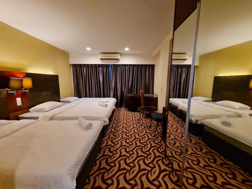 a hotel room with four beds in a room at SUN GARDEN Studio and Residences at South China Sea Place Suites in Kota Kinabalu