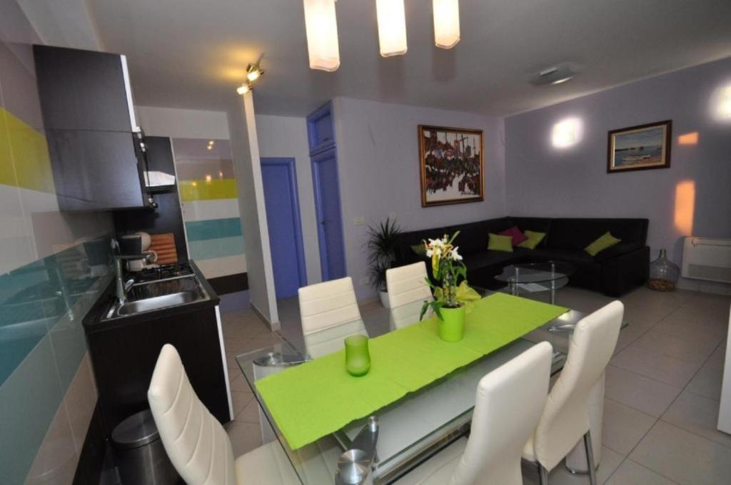 a kitchen and living room with a green table and chairs at Apartments Njoko - sea view in Prvić Šepurine