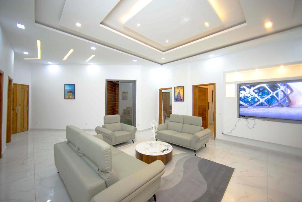 salon z kanapą, 2 krzesłami i telewizorem w obiekcie RESIDENCE TERANGA immo luxe w mieście Dakar