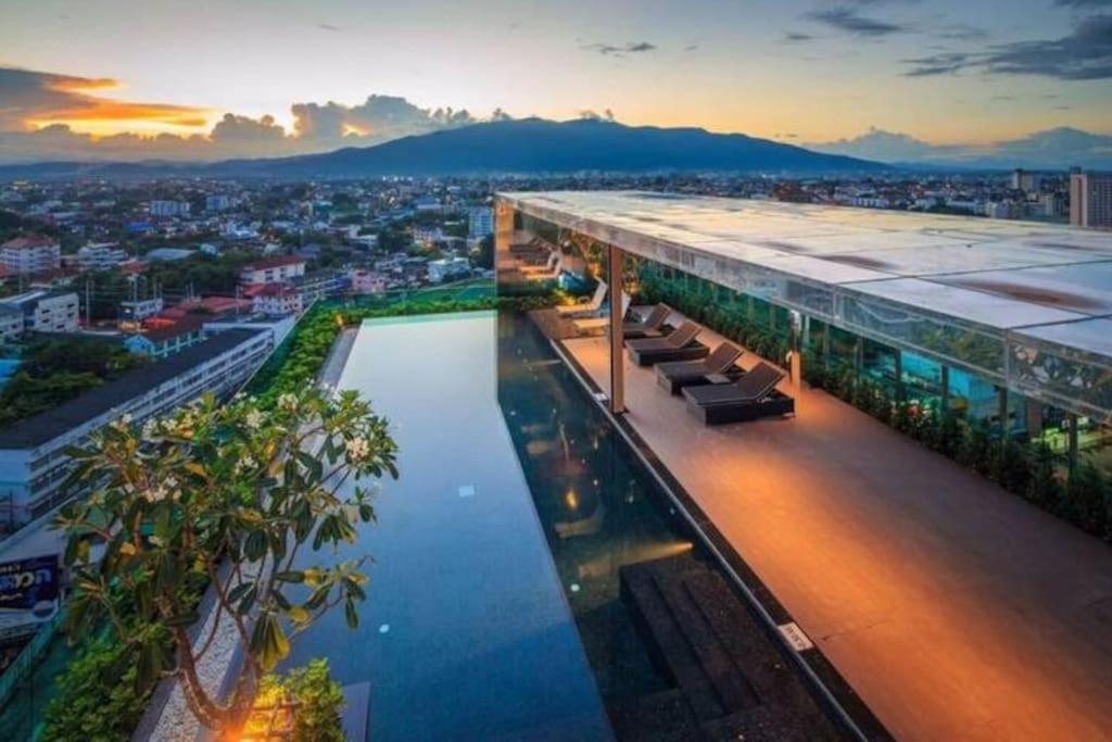 un edificio con una piscina d'acqua di fronte ad una città di The Astra Condo Changkhlan in Chiang Mai a Chiang Mai