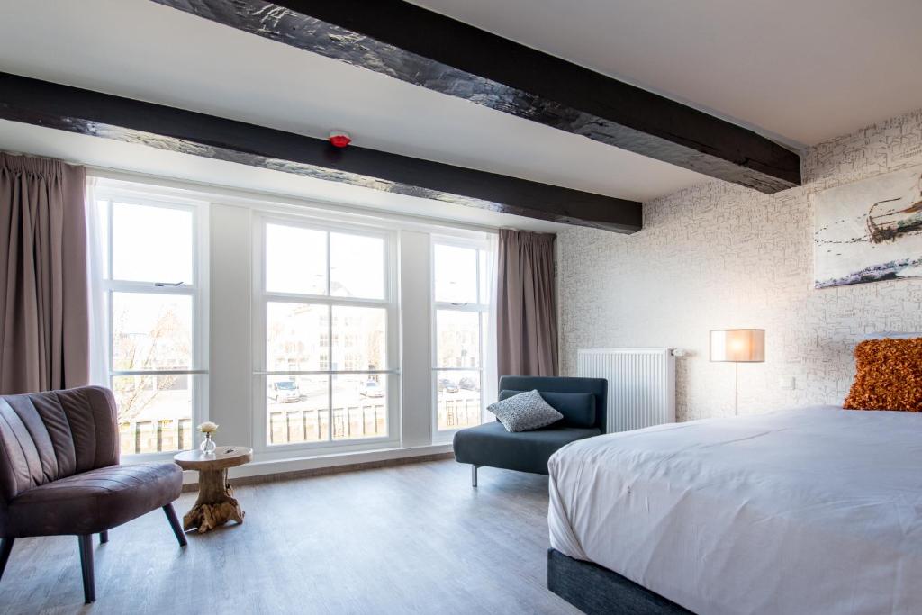um quarto com uma cama, uma cadeira e uma janela em Boutique Hotel De Eilanden em Harlingen