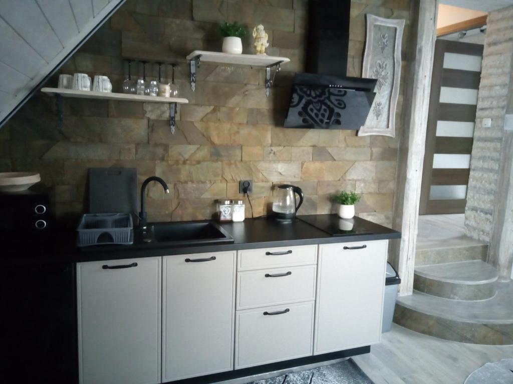 - une cuisine avec des placards blancs et un mur en pierre dans l'établissement Apartament u Busiów - okolice Zakopanego, à Dzianisz