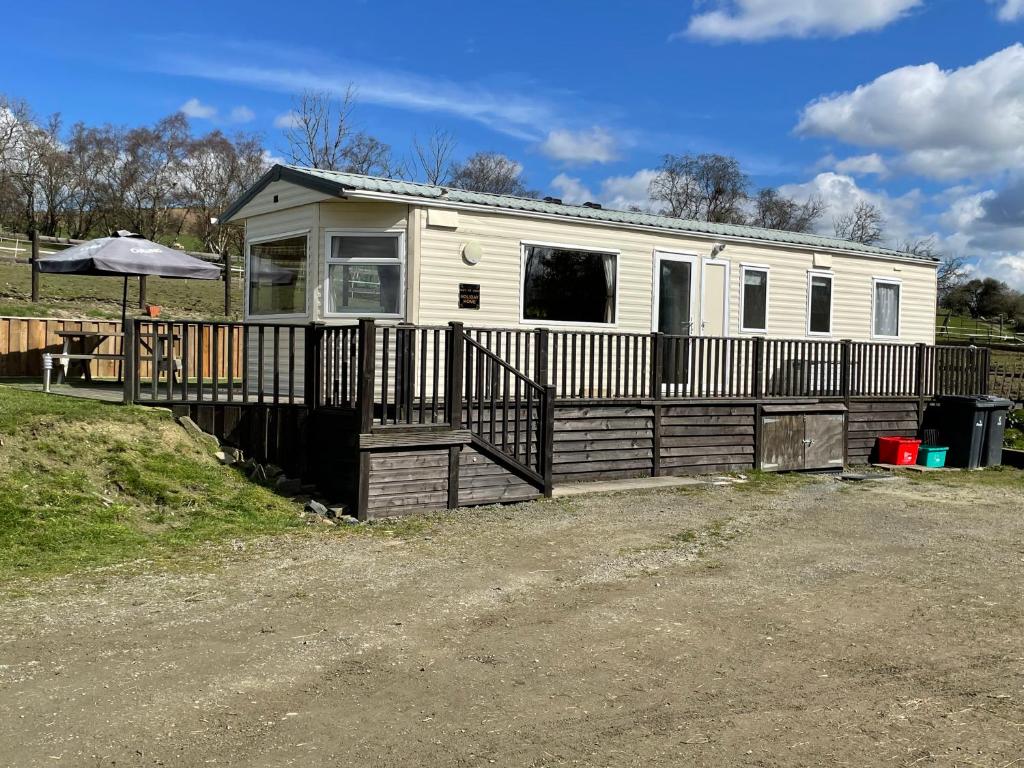 a mobile home with a fence and an umbrella at Pant yr onen holidays in Llandrindod Wells