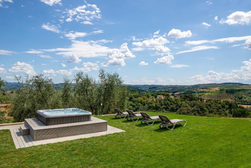 a group of chairs sitting on a lawn with a pool at Live Tuscany! Apartment on the hills of Florence! in Ginestra