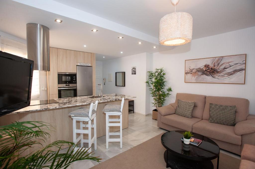 sala de estar con sofá y cocina con barra. en Penthouse with terrace in Marbella- Costa del Sol, en Marbella