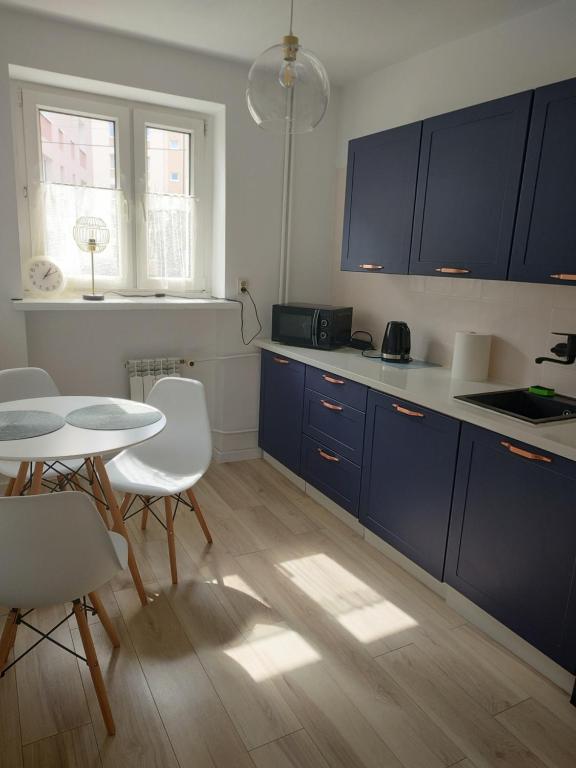 a kitchen with blue cabinets and a table and chairs at Apartament centrum in Szczytno