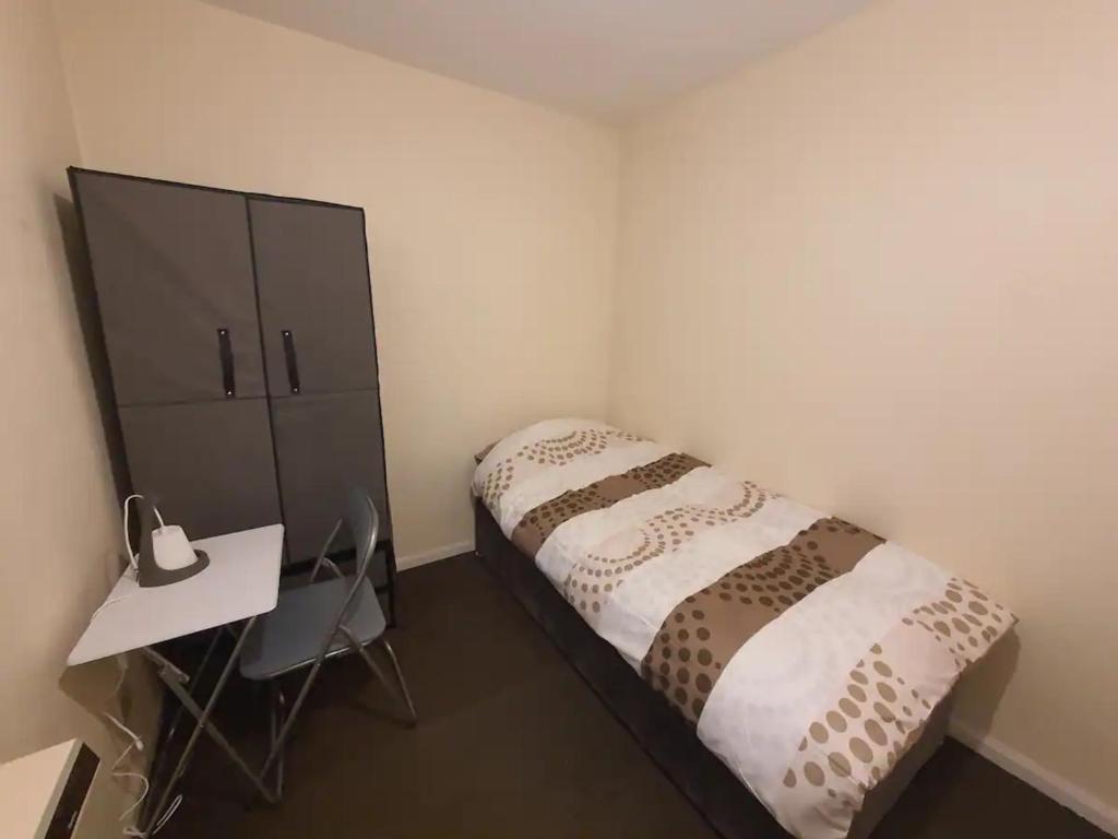 um pequeno quarto com uma cama e uma secretária em Spacious Single bed Manchester em Middleton