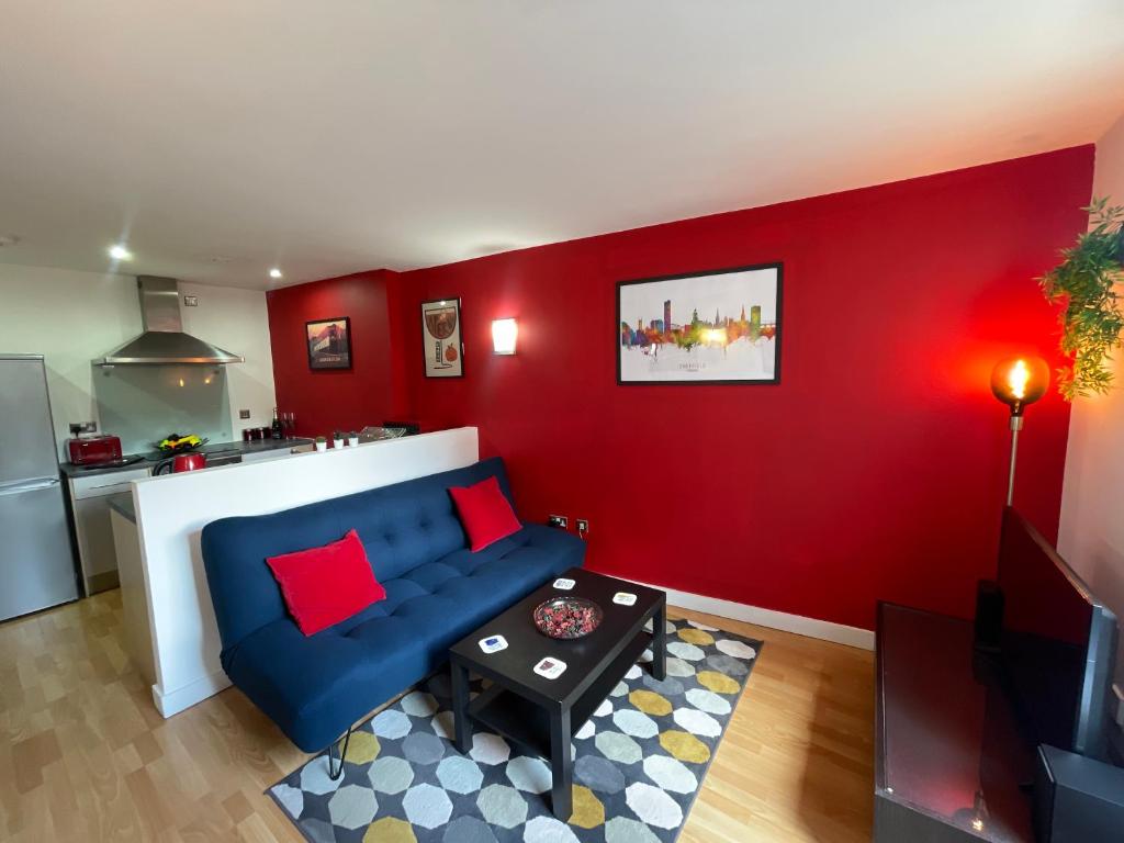 a living room with a blue couch and a red wall at Iconic City Centre Apartment in the Devonshire Quarter in Sheffield