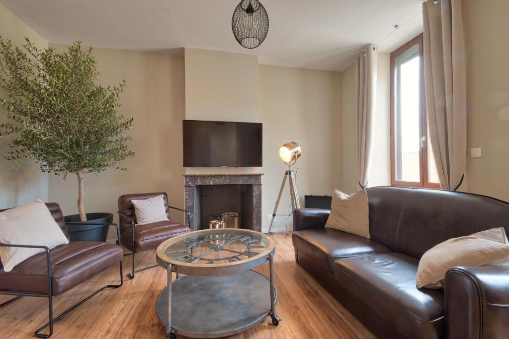 a living room with a leather couch and a table at Appartement Complet Rez-de-chaussée in Sains-Richaumont