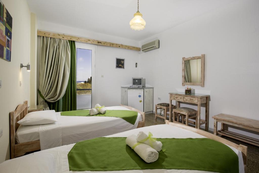 Kalathos Sun Hotel في كالاثوس: غرفة فندقية بسريرين بملاءات خضراء