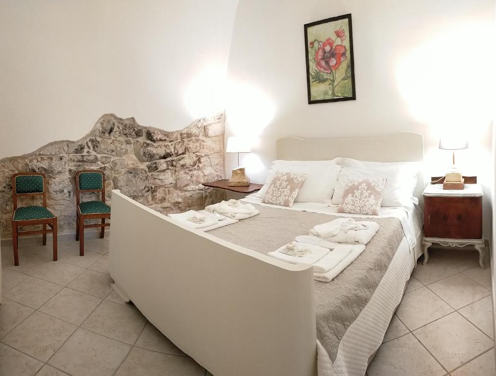 a bedroom with a large white bed and chairs at Villa Sportelli - Antica Dimora in Selva di Fasano