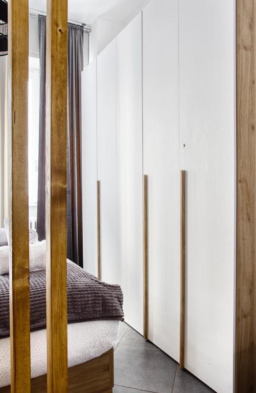 a bedroom with white walls and wooden dividers at C Studio - Design Bilo Suite -M3- 8 min dal Duomo in Milan