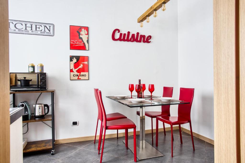 a table with red chairs and wine glasses on it at C Studio - Design Bilo Suite -M3- 8 min dal Duomo in Milan