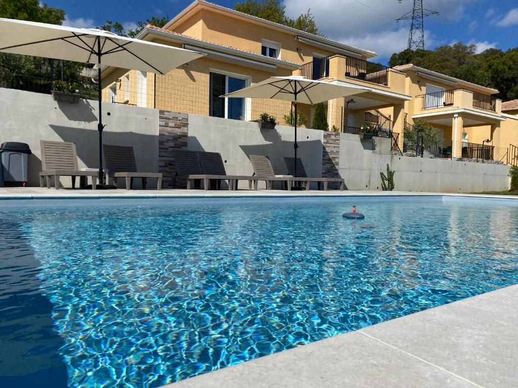 a swimming pool with umbrellas in front of a house at Résidence Pasturella in Bastia