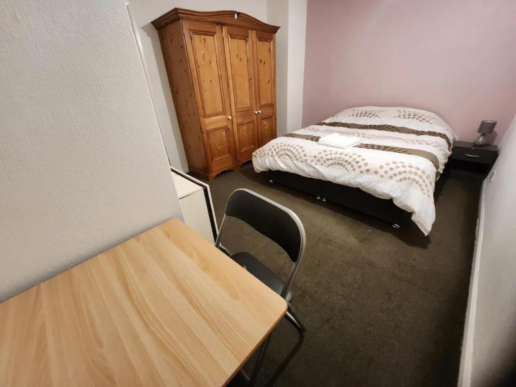 a small room with a bed and a wooden cabinet at Spacious DoubleBedroom Manchester in Middleton