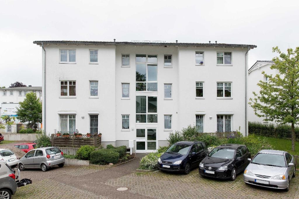 a white house with cars parked in front of it at Appartement Granitz - Ferienwohnung Thoenissen in Göhren