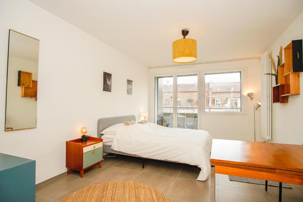 a white bedroom with a bed and a window at Stylish apartment with free BaselCard in Basel
