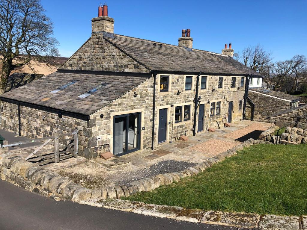 um velho edifício de pedra no lado de uma estrada em Bess Cottage em Hebden Bridge