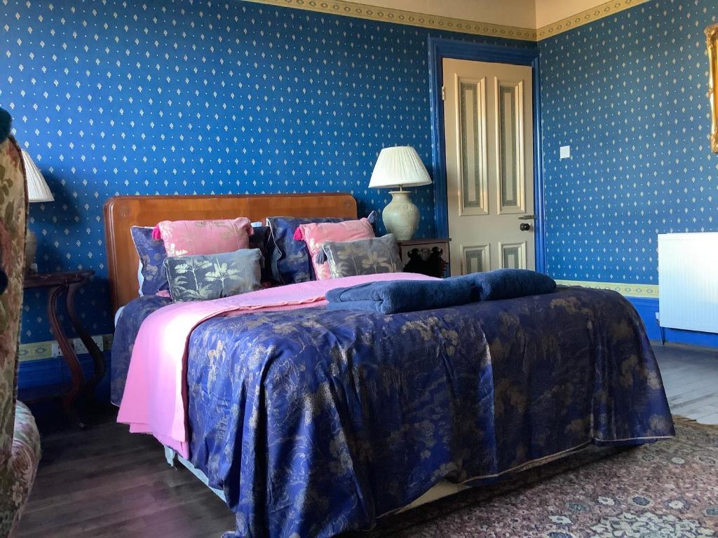 a bedroom with a large bed with blue walls at Rooms or Entire City House 6min drive to Stadium of Light in Sunderland