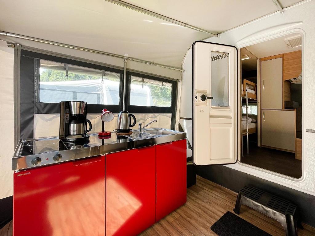 a kitchen in an rv with a red cabinet at Mietwohnwagen 01 in Heringsdorf