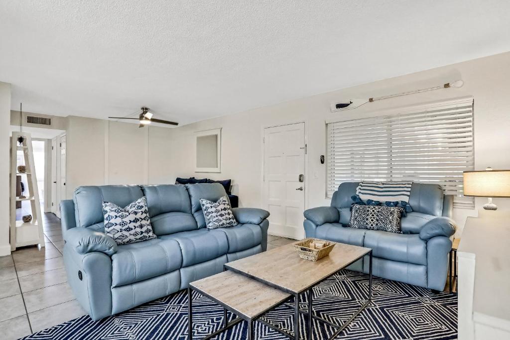 una sala de estar con 2 sofás azules y una mesa. en Waves Unit 2, en St Pete Beach