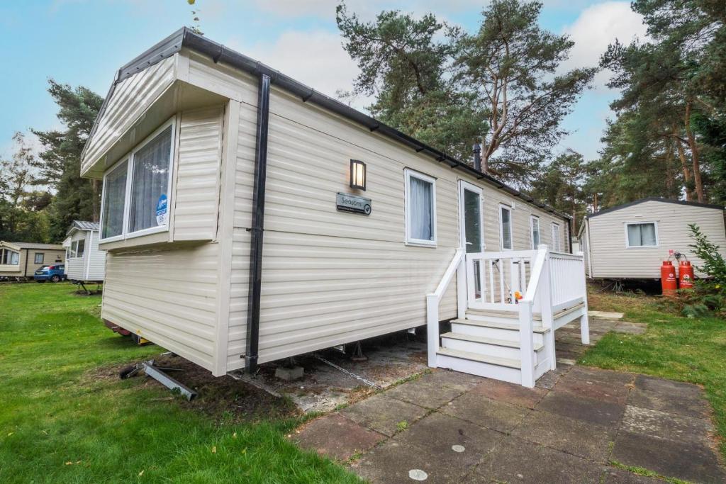 a white tiny house with a staircase in a yard at Beautiful 8 Berth Caravan At Wild Duck Haven Park In Norfolk Ref 11195sc in Great Yarmouth