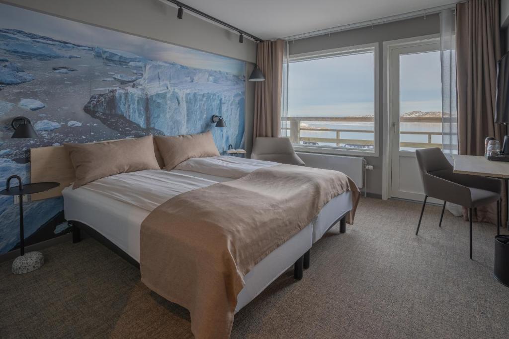 ein Schlafzimmer mit einem großen Bett und einem Gemälde an der Wand in der Unterkunft Hotel Hvide Falk in Ilulissat