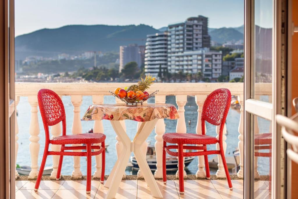 un tavolo con 4 sedie e un cesto di frutta sul balcone di ACIKA apartments a Rafailovici