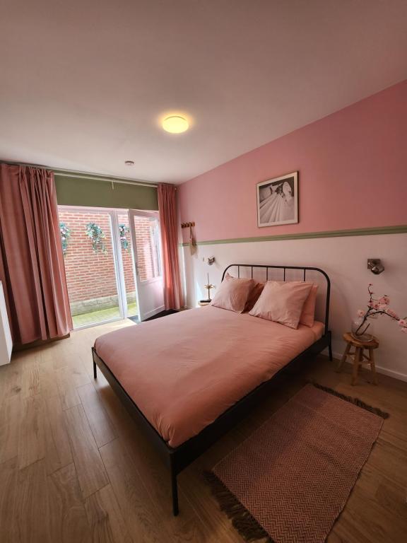 sypialnia z łóżkiem z różowymi ścianami i oknem w obiekcie Bed & Stay Kersenbloesem w mieście Nijswiller